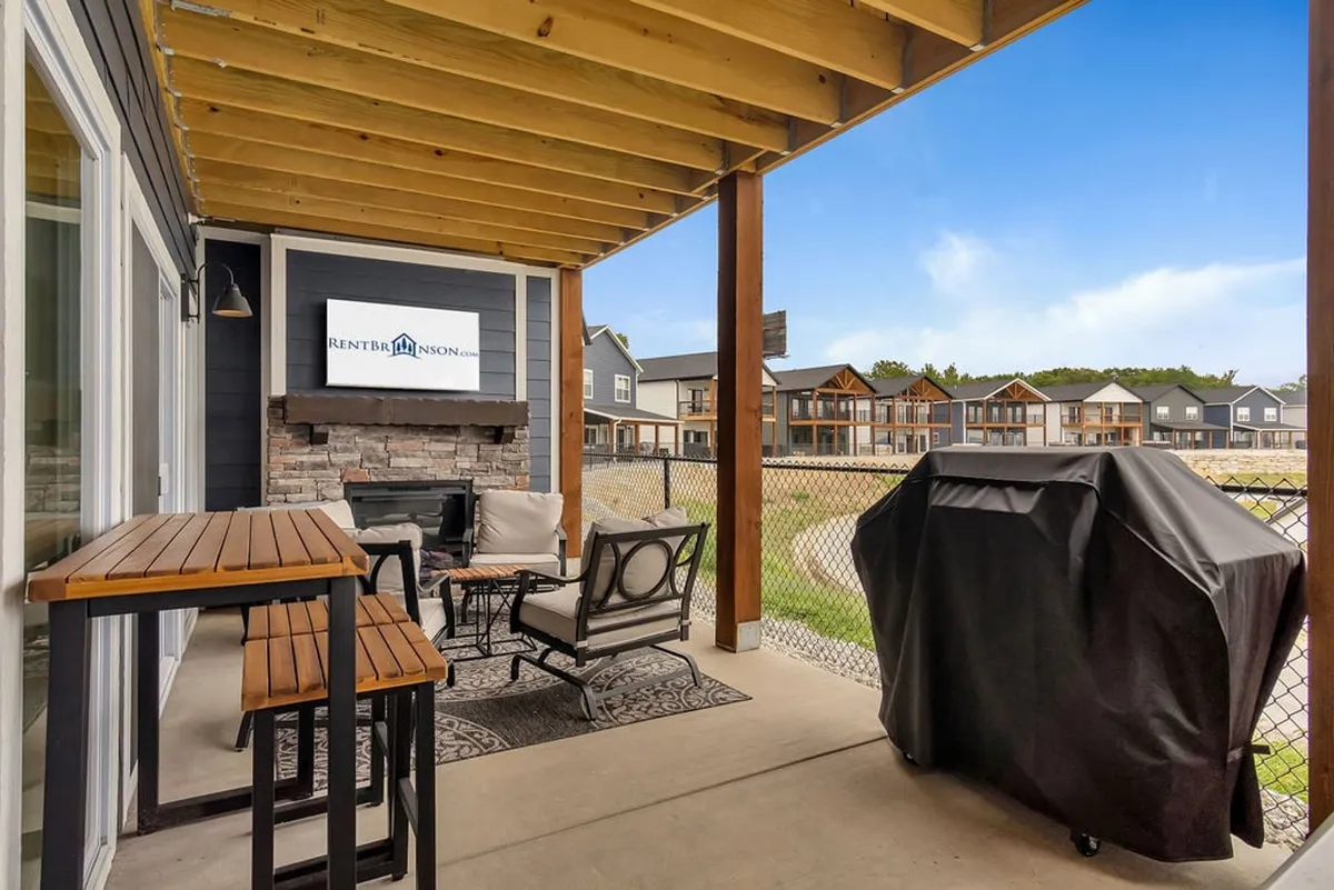 A vibrant outdoor seating area featuring a fireplace, grill, and a television screen. The setup is designed for barbecuing, entertaining, and watching the big game outdoors. It's an ideal spot for family gatherings, alfresco feasts, and memorable evenings under the stars.