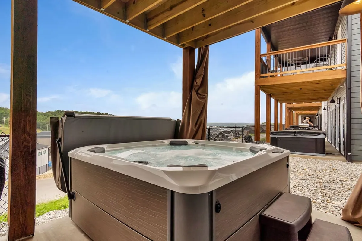 This image captures a serene outdoor hot tub set on a wooden deck, surrounded by natural landscape. The setting evokes relaxation, socializing, and enjoying scenic views—ideal for unwinding after a day of golf or lake adventures.