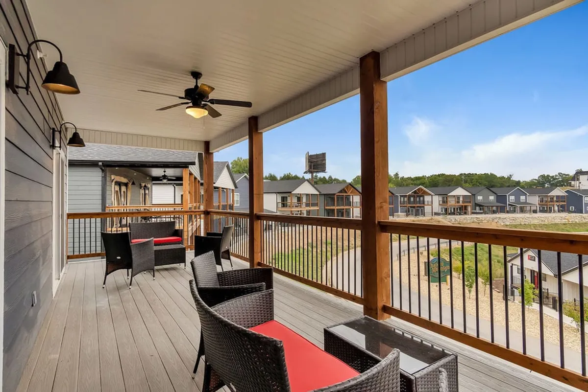 This image offers a view of a spacious outdoor seating area on a wooden deck, overlooking surrounding homes under an open sky. The space invites relaxation, conversation, and connection to the neighborhood or natural surroundings.